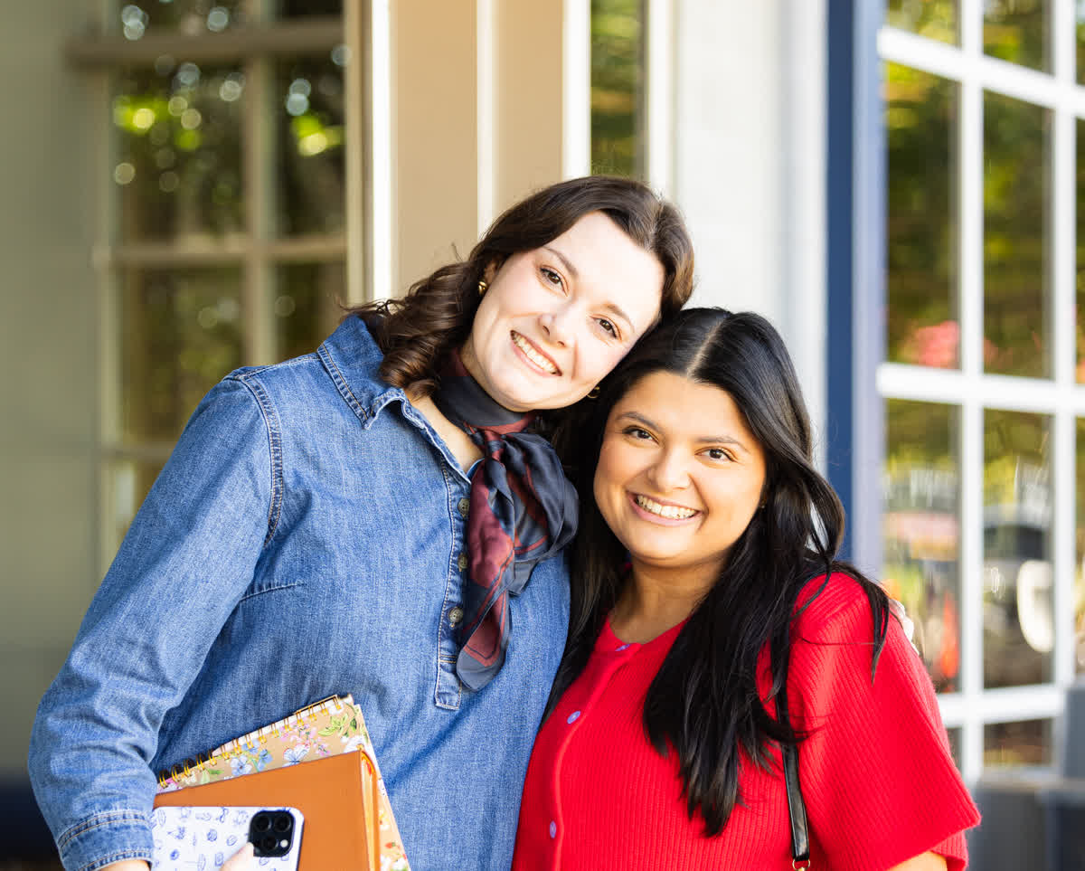 Two friends smiling together outside a Rise Church service